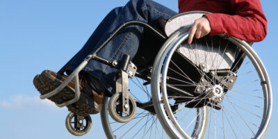 image of a manual wheelchair user popping a wheelie